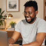 Smiling man working on a laptop in a bright home office