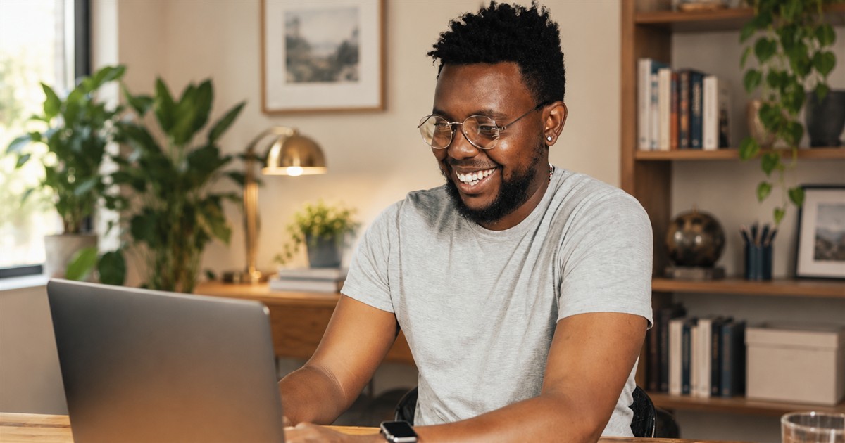 Smiling man working on a laptop in a bright home office