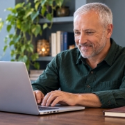 Psychic affiliates — working at a laptop A mature man typing on a laptop with both hands in a blue-gray office